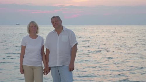 Senior Couple By Sea Looking To the Camera
