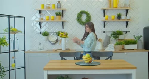 Woman Dancing in Bright Kitchen, Listening to Music