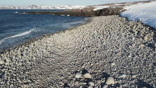 Winter Aerial Flight Top Over Waves Rolling on Artic Ocean Shore with Round Stones Ocean Waves at