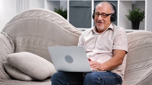Senior Man on Laptop Video Call with Headphones