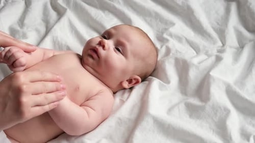 Infant Getting Loving Tummy Massage on White Blanket