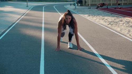 Focused Woman on Running Track Getting Ready to Sprint