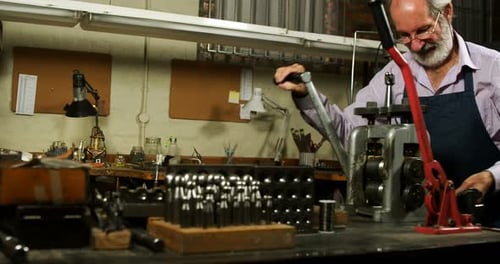 Goldsmith working on machine in workshop