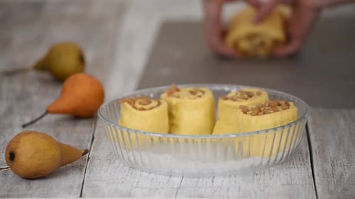 Baker Put Pear Roll Buns Into Glass Baking Form. Woman Makes a Yeast Sweet Roll Buns