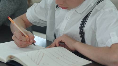 Mains de garçon faisant leurs devoirs