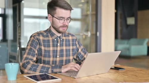 Young Designer Using Laptop in Modern Office