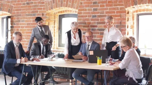 Eight Businessmen Discussing New Project in Office with Brick Walls