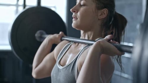 Strong Woman Lifting Barbell in a Gym