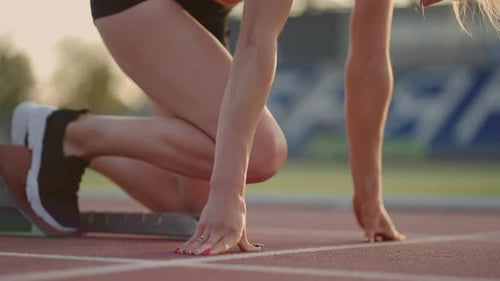 Female Athlete Starting Block on Red Running Track