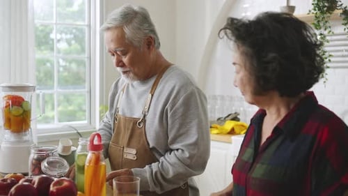 Elderly Couple Prepares Nutritious Drink in Bright Kitchen