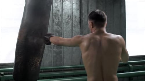 Muscular Man Punching Bag in Urban Gym