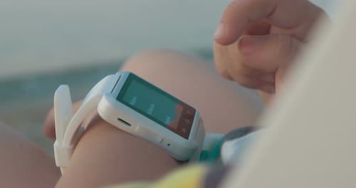 Child Using Smartwatch on Beach, Close Up