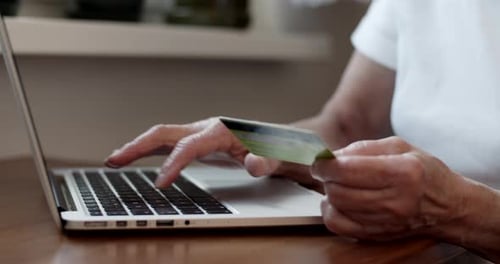 Adult Types on Laptop While Holding Credit Card