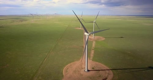 Aerial of wind turbine blades rotating in the wind farm, wide shot