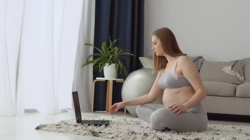 Pregnant Woman Meditating with Laptop in Home