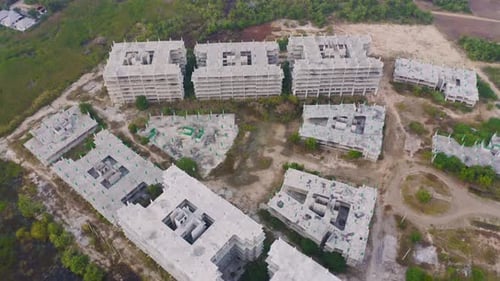 Aerial top view of abandoned apartment or hotel under construction site with structure.