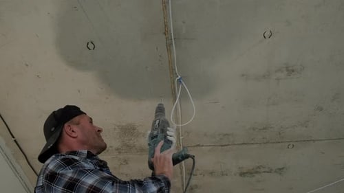 Man Drilling Into Concrete Ceiling with Electric Drill