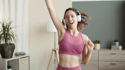 Woman Dancing Energetically with Headphones in Living Room