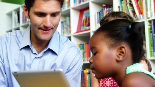 Teacher and schoolkids using digital tablet in library at school