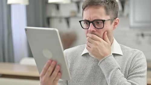 Man Using Tablet Reacts with Surprise Indoors