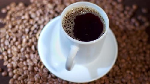 A Cup of Steaming Hot Coffee Standing on Arabica Beans