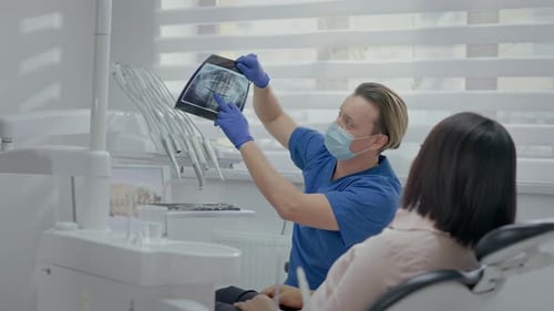 Dentist Reviews X-Ray with Patient in Modern Office