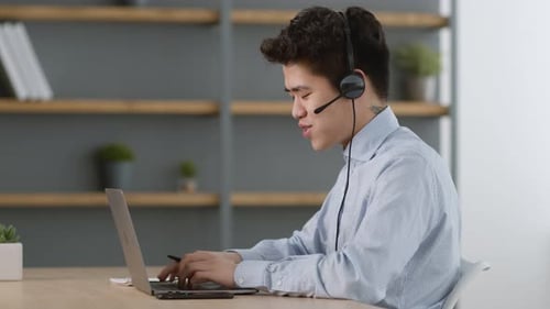 Young Adult Working at Computer with Headset