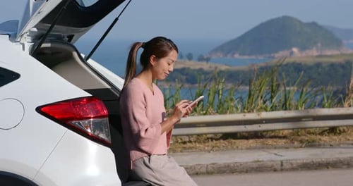 Woman use of mobile phone for her road trip at countryside