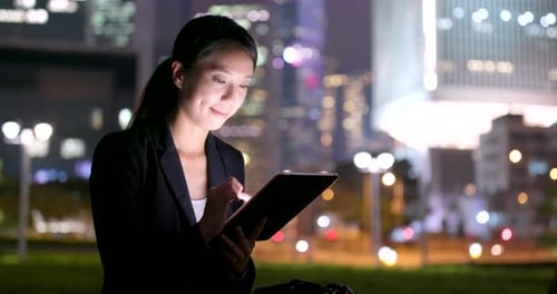 Woman Using Tablet in City at Night