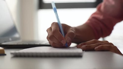 Closeup Cropped Shot of Unrecognizable Businessman Writing in Notebook Sitting in Front of Laptop