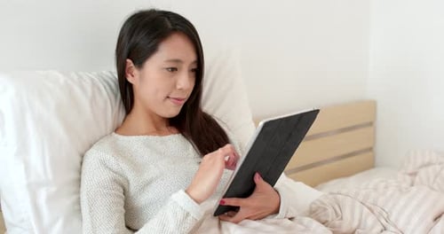 Woman Uses Tablet in Bed at Home