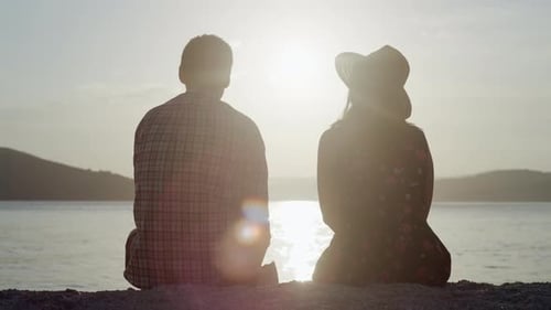 A Man and a Woman are Sitting at Sunset By the Sea