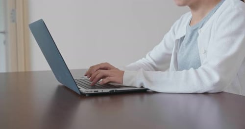 Woman Typing on Laptop Computer at Table Indoors