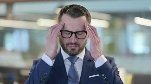 Stressed Businessman Rubbing Temples in Office Close Up