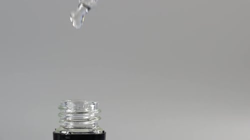 Clear Liquid Dropping from Glass Dropper into Bottle