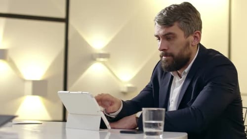 Man Concentrating on Tablet in Modern Office