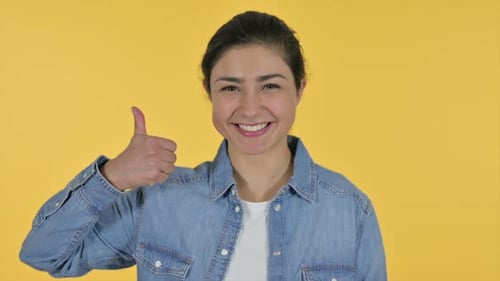 Smiling Woman Gives Thumbs Up on Yellow Background