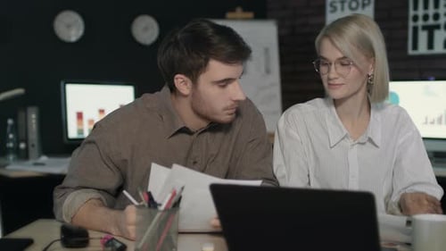 Business Partner Discussing Financial Reports in Front of Laptop in Night Office
