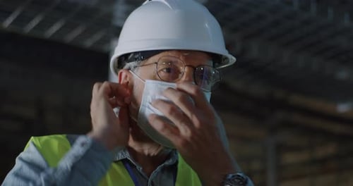 Man Puts on Safety Mask in Industrial Setting