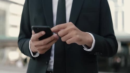Adult in Suit Texting on Phone in City