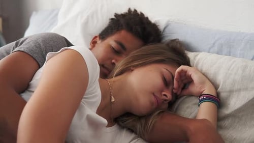 Closeup View of Multiracial Couple Lying in Bed and Sleeping While Embracing Each Other