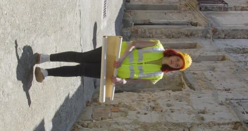 Vertical video of a girl engineer looking at the blueprint on paper