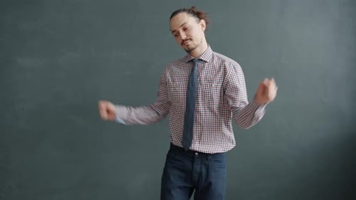 Portrait of Handsome Young Man Dancing Against Grey Background Having Fun