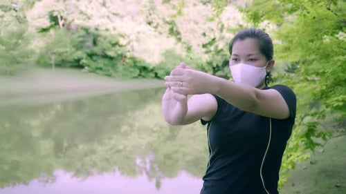 Asian woman exercise in park outdoor with new normal in COVID-19 situation