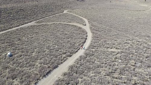 Aerial shot of a young man and woman trail running with dog on scenic mountain trail