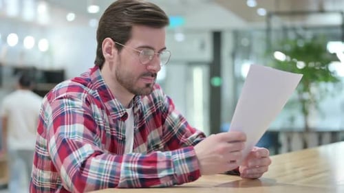 Excited Young Man Reading Document in Office