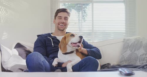Man Smiling Holding Beagle Dog on Couch Indoors