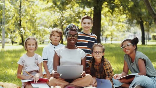 Happy Multiethnic Schoolchildren and Female Teacher Posing Together in Park
