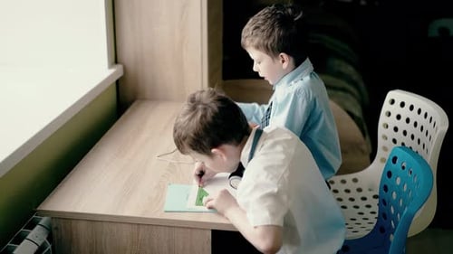 Two Young Boys Drawing and Using Tablet Indoors