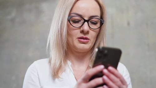 Caucasian Woman with Smartphone in Hands Beautiful Business Woman with Glasses in Office